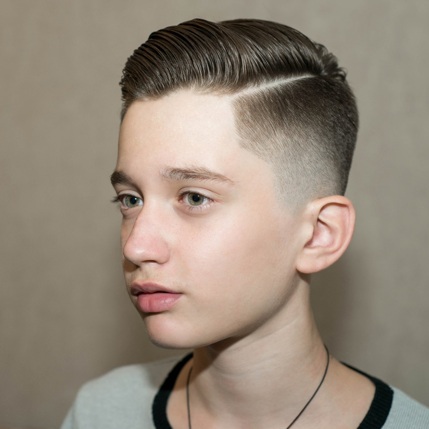 Stylish modern retro haircut side part with mid fade with parting of a school boy